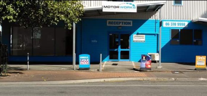 The blue Motorworks building on Russell Street, Masterton, seen from across the road, with the reception entrance and a Liqui Moly sign on the footpath