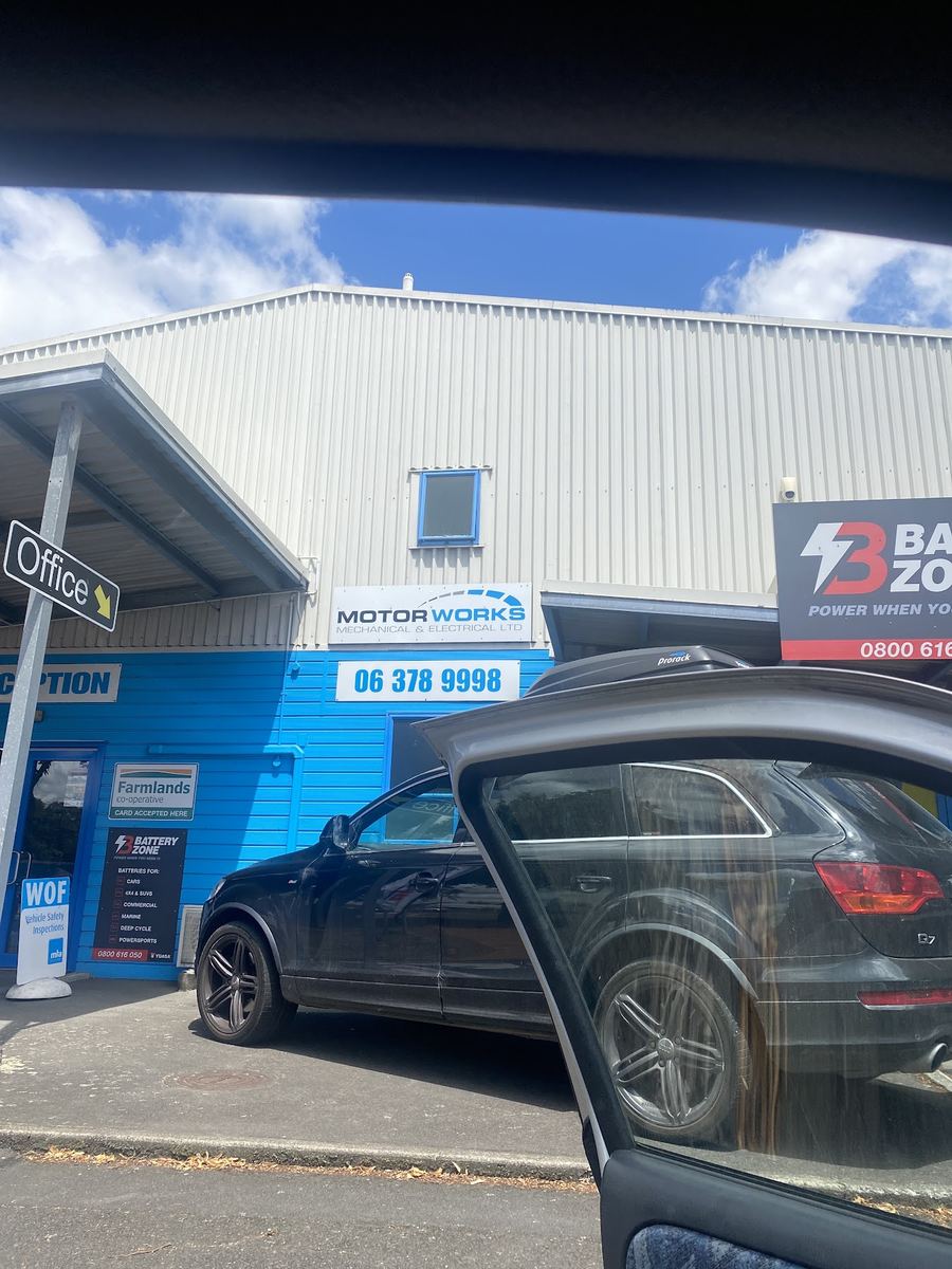 The Motorworks reception entrance on Russell Street, with the WOF vehicle safety inspection sign, Battery Zone signage and a car waiting outside